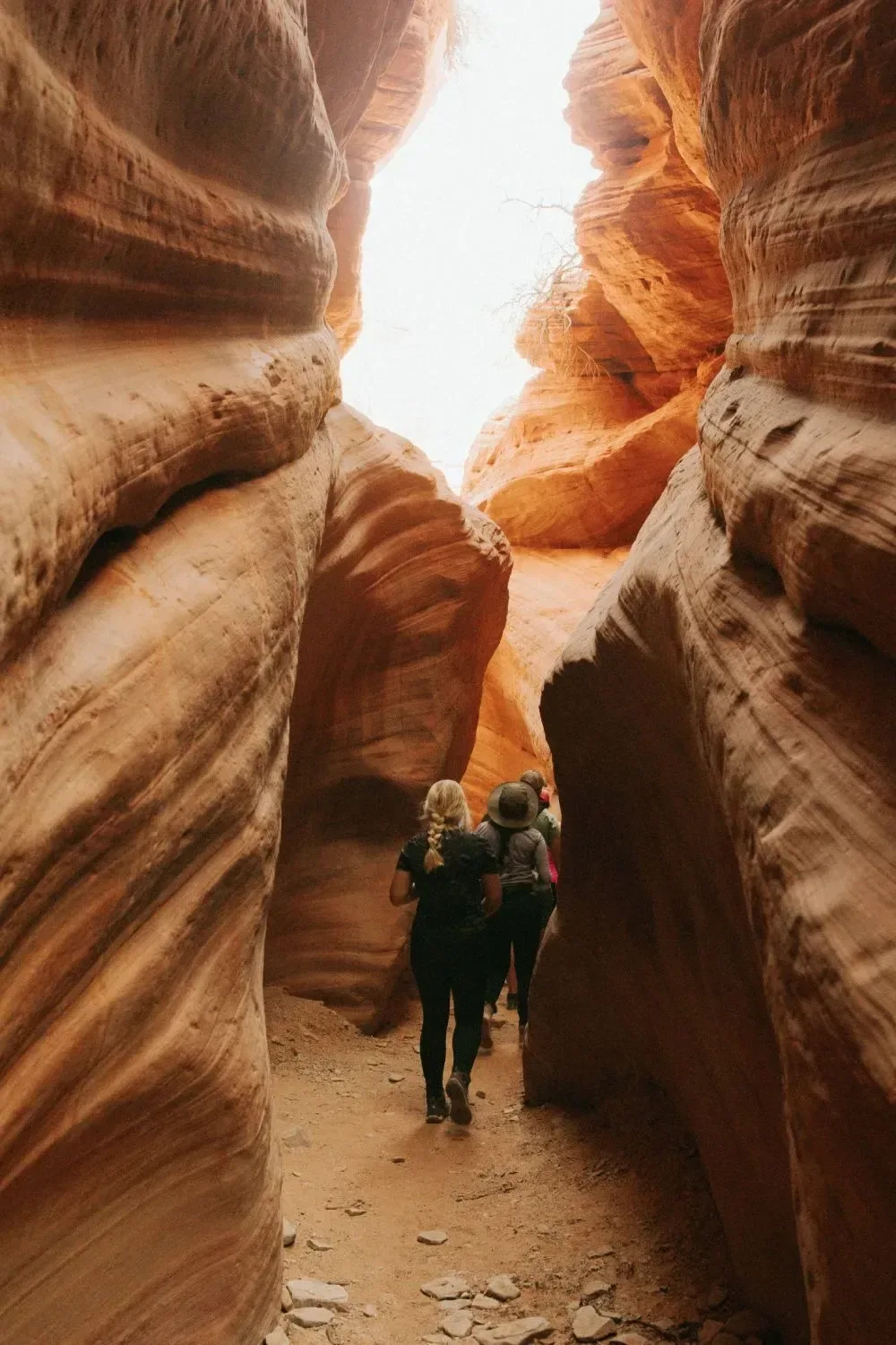 Two guests walking between the glowing red walls of Peekaboo Slot Canyon