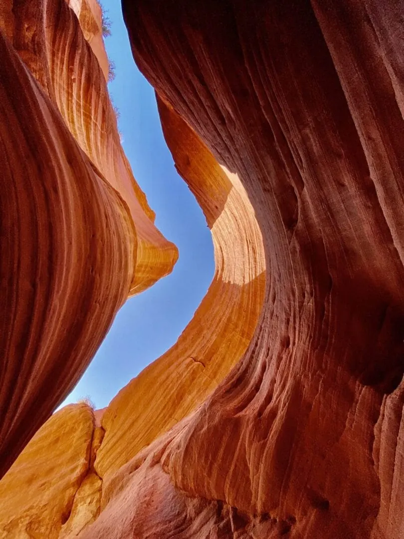 Looking up at a sliver of blue sky between the red walls of Peekaboo Slot Canyon
