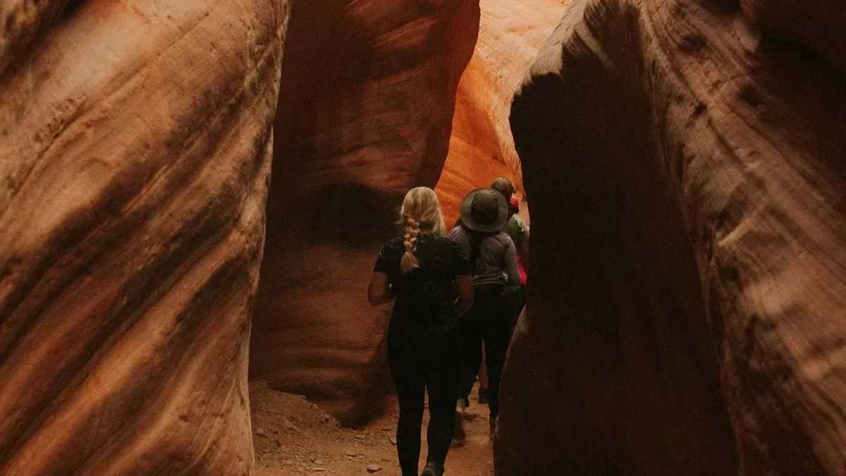 Guests walking between the tall red walls of Peekaboo Slot Canyon